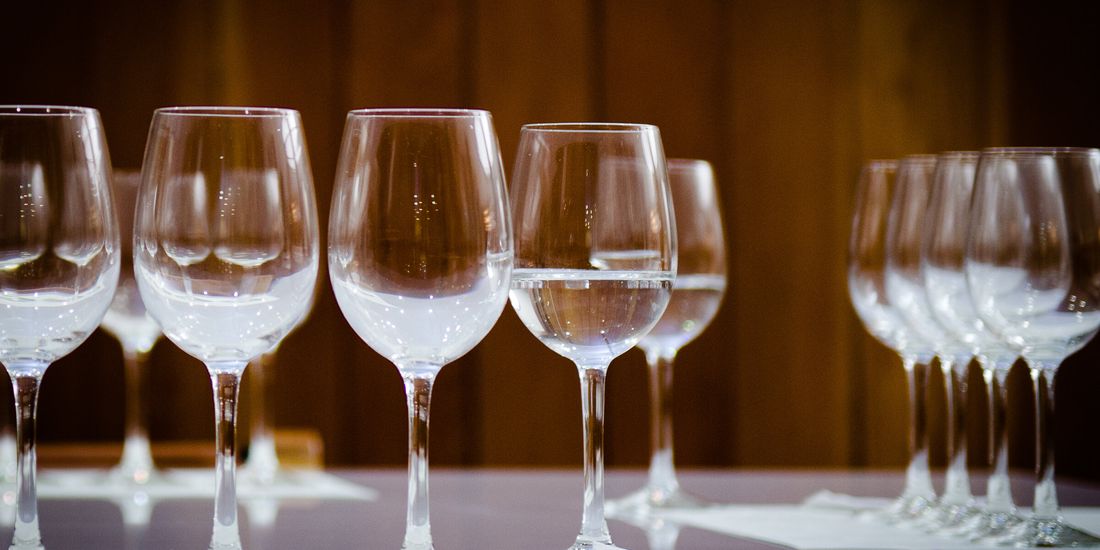 Empty tasting glasses lined up on a wooden table before a side-by-side tasting
